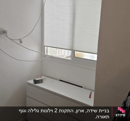 מזגן מותקן על קיר מעל שידה לבנה